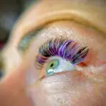 Detailaufnahme einer Wimpernverlängerung mit teilweise lila farbigen Wimpernextensions